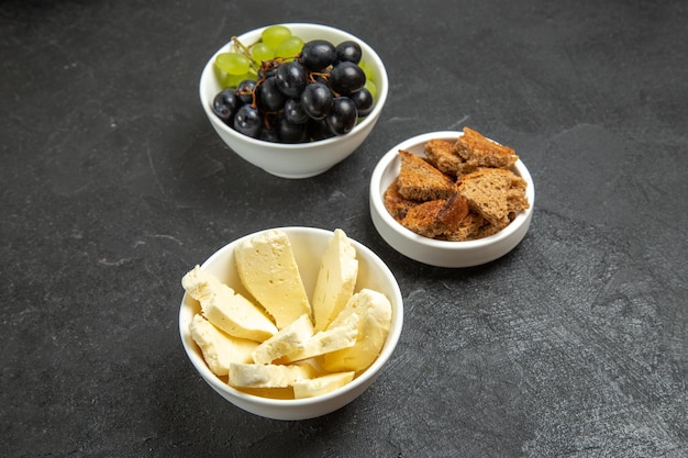 Vue de face des raisins frais avec du fromage blanc et du pain noir tranché sur un bureau sombre repas plat de fruits au lait