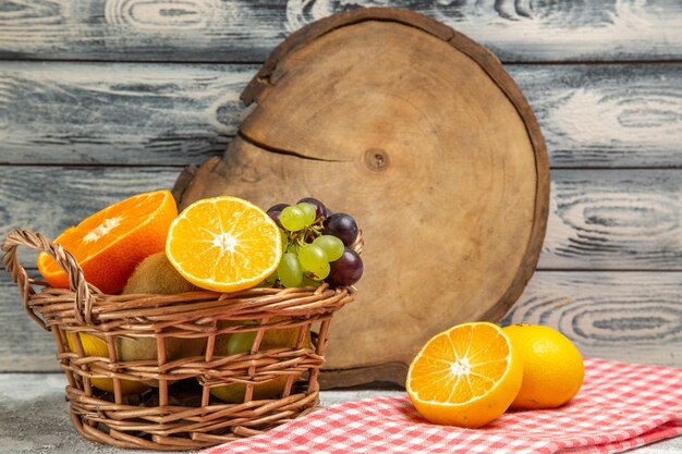 Vue de face des raisins de fruits frais et des tranches d'oranges à l'intérieur du panier sur fond blanc fruits mûrs mûrs vitamine frais