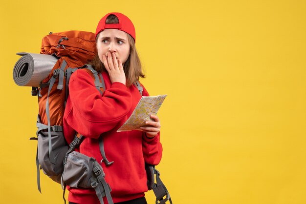 Vue de face de la randonneuse inquiète avec sac à dos rouge tenant la carte