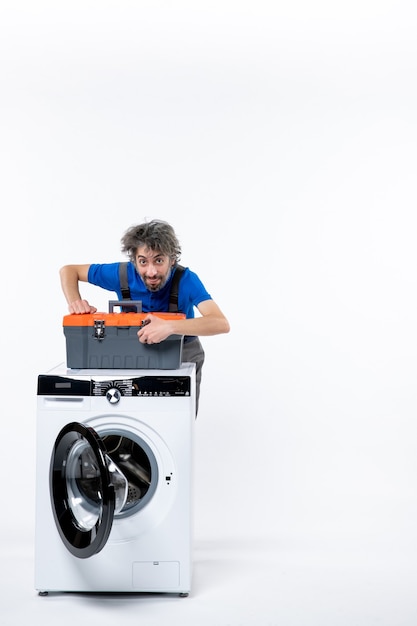 Vue de face réparateur masculin mettant le sac d'outils sur la machine à laver sur l'espace blanc