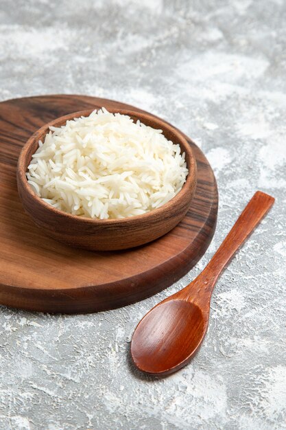 Vue de face riz cuit délicieux à l'intérieur de la plaque sur un bureau blanc