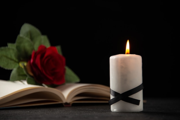 Vue de face de rose rouge avec livre et bougie sur fond noir