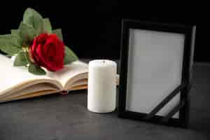 Photo gratuite vue de face de la rose rouge avec livre et cadre photo sur fond noir