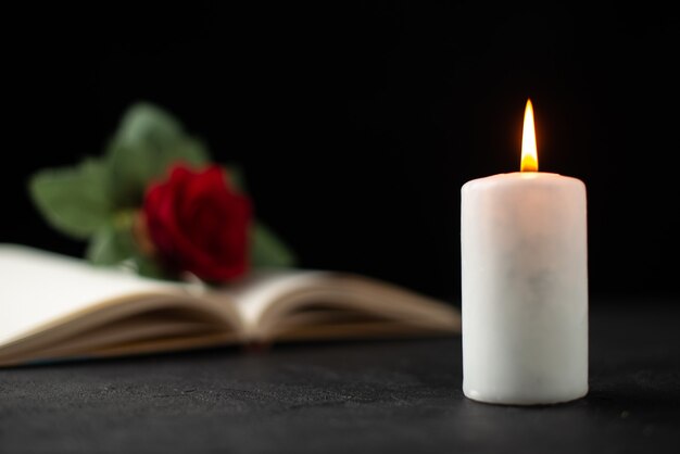 Vue de face de rose rouge avec livre ouvert et bougie sur fond noir