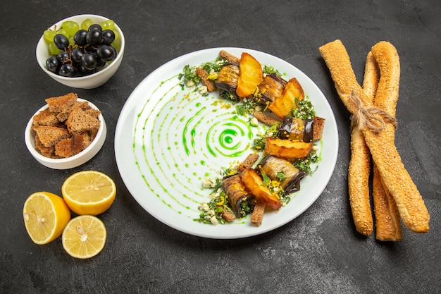 Vue de face des rouleaux d'aubergines cuites avec des raisins et des tranches de citron sur fond sombre plat dîner repas fruits cuisson