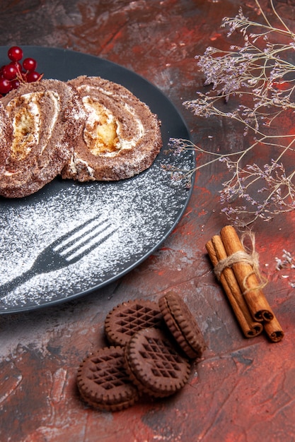 Photo gratuite vue de face des rouleaux de biscuits avec des cookies sur une surface sombre