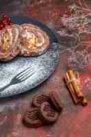 Photo gratuite vue de face des rouleaux de biscuits avec des cookies sur une surface sombre