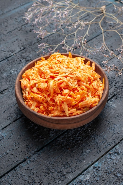 Vue de face de la salade de carottes râpées à l'intérieur de la plaque brune sur le bureau rustique bleu foncé couleur salade de santé régime de légumes mûrs