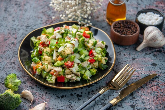 Vue de face salade de légumes avec des assaisonnements et de l'ail sur une surface sombre restaurant alimentaire cuisine fraîche déjeuner couleur santé alimentation