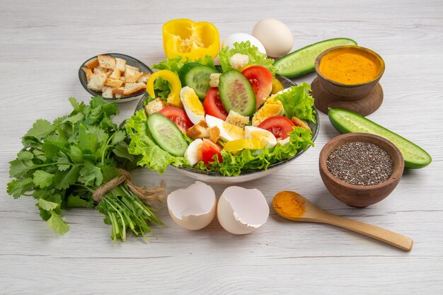 Vue de face salade de légumes savoureuse avec oeufs verts et assaisonnements sur fond blanc repas nourriture petit déjeuner couleur mûre