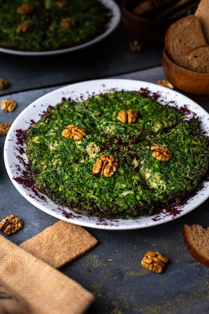 Photo gratuite une vue de face salade de poulet aux noix et verts à l'intérieur de la plaque blanche avec des miches de pain chips sur le bureau gris légume salade mayyonaise