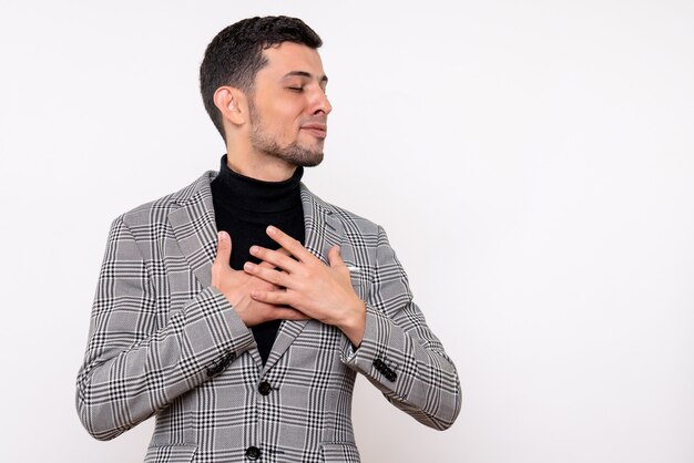 Vue de face satisfait beau mâle en costume fermant les yeux debout sur fond blanc