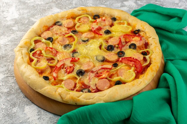 Vue de face savoureuse pizza au fromage avec saucisses aux olives noires et tomates rouges sur bureau gris