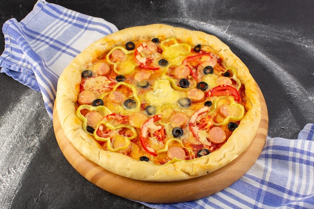 Vue de face savoureuse pizza au fromage avec tomates rouges olives noires et saucisses sur dark