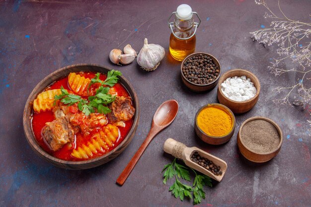 Vue de face savoureuse sauce à la viande avec différents assaisonnements sur une surface sombre sauce plat soupe dîner nourriture