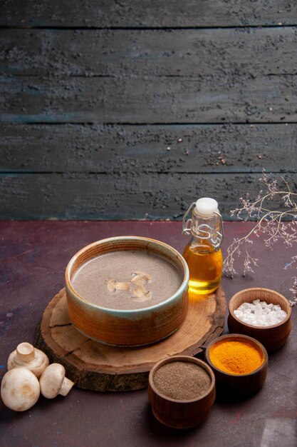 Vue de face savoureuse soupe aux champignons avec différents assaisonnements sur l'espace sombre