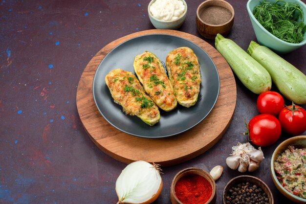 Vue de face de savoureuses courges cuites au four avec des légumes verts avec des assaisonnements et des légumes frais sur le bureau sombre.