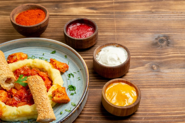 Vue de face de savoureuses tranches de viande avec purée de pommes de terre et assaisonnements sur un plat de bureau brun repas de viande pain de pommes de terre nourriture