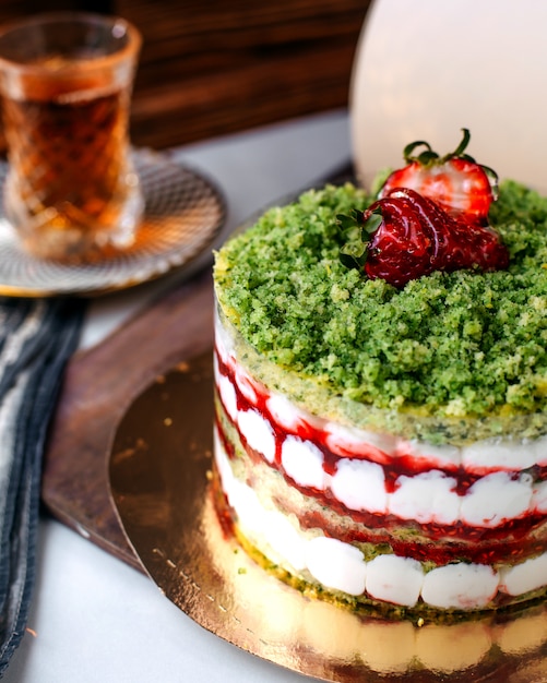 Vue de face savoureux gâteau aux fruits de couleur gâteau avec du thé chaud sur le plancher clair