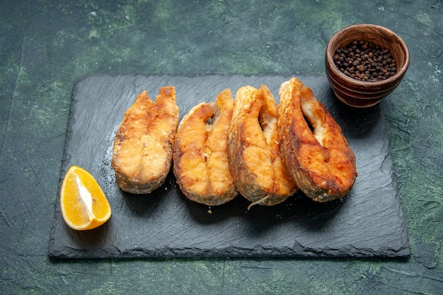 Vue de face savoureux poisson frit sur une surface sombre repas de la viande de poivre de cuisson friture de fruits de mer plat de salade