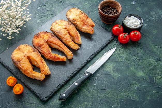 Vue de face savoureux poisson frit avec des tomates sur un plat de surface sombre salade alimentaire frire la viande de poivre de mer repas de cuisine fruits de mer