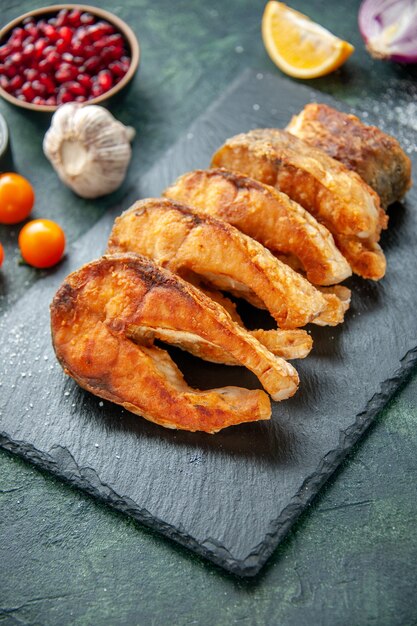 Vue de face savoureux poisson frit avec des tomates sur la surface bleu foncé repas poivron cuisson friture fruits de mer viande de mer salade alimentaire