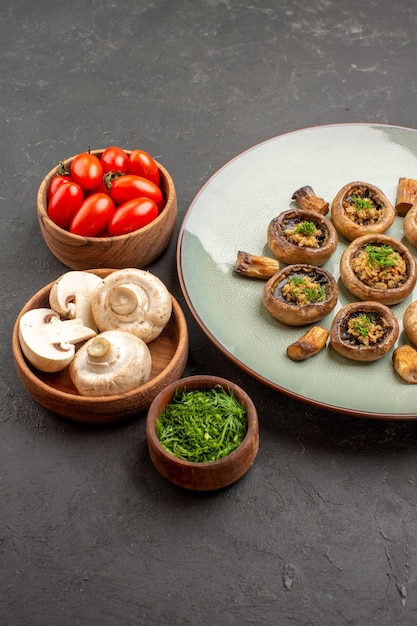 Vue de face savoureux repas de champignons avec des légumes verts frais et des tomates sur le plat de fond sombre dîner repas cuisson champignon