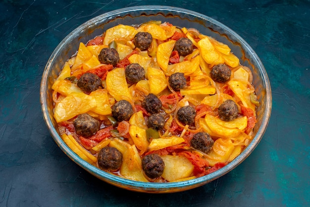 Vue de face savoureux repas de pommes de terre avec des boulettes de viande et des tomates sur fond bleu foncé.