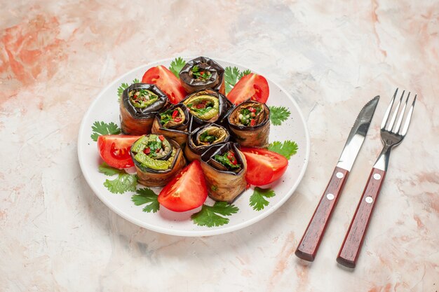 Vue de face de savoureux rouleaux d'aubergines avec des verts et des tomates