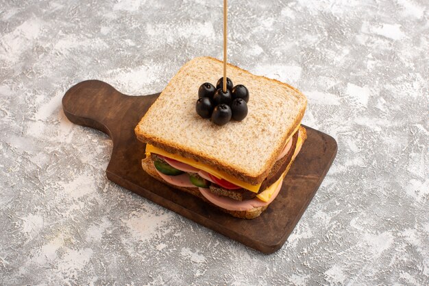 Vue de face savoureux sandwich avec tomates jambon olive légumes sur bâton