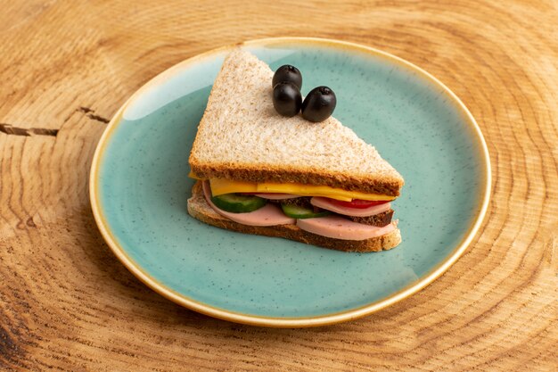 Vue de face savoureux sandwich avec tomates jambon olive légumes sur bois