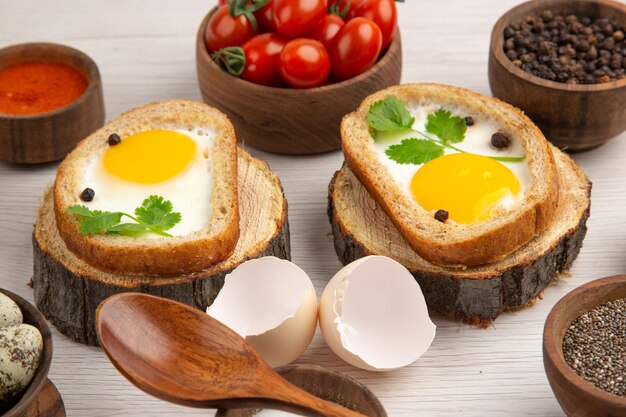 Vue de face de savoureux toasts aux œufs avec assaisonnements et tomates sur fond blanc photo repas du matin couleur petit déjeuner nourriture déjeuner salade