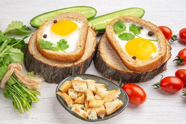 Vue de face savoureux toasts aux œufs avec des verts et des légumes sur fond blanc déjeuner aliments mûrs petit déjeuner salade régime vie saine repas