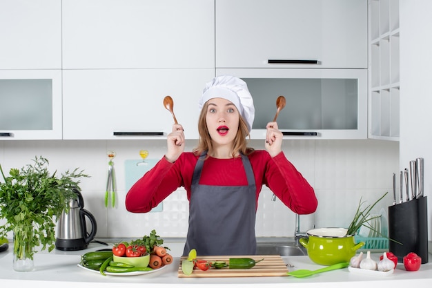 Photo gratuite vue de face se demandait chef féminin en tablier tenant des cuillères