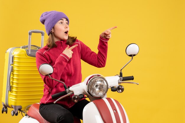 Vue de face se demandait jeune femme sur un cyclomoteur en montrant quelque chose