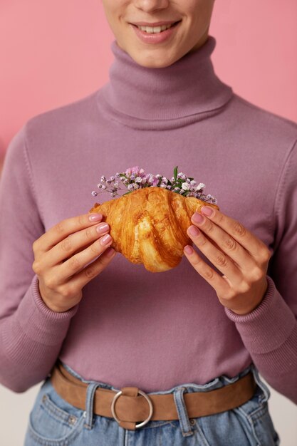 Vue de face smiley adulte tenant un croissant