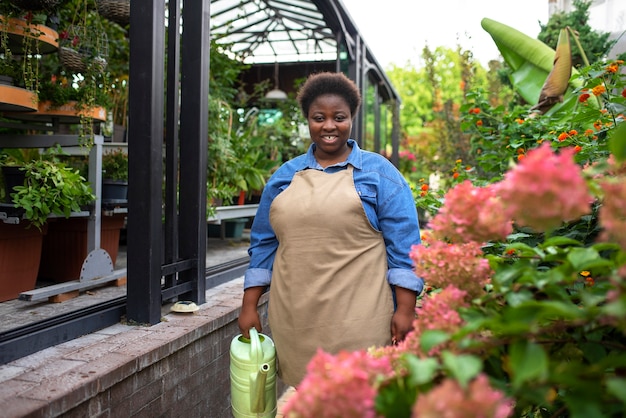 Photo gratuite vue de face smiley femme noire qui dirige une entreprise de fleurs