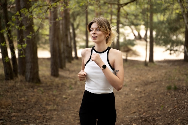 Vue de face smiley femme qui court dans la nature