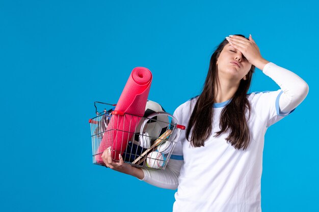 Vue de face a souligné jeune femme avec panier plein de choses sportives