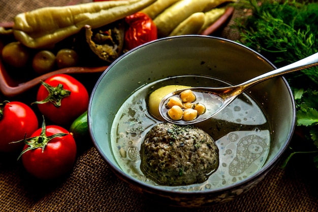 Vue de face soupe kufta-bozbash soupe traditionnelle azerbaïdjanaise servie avec des tomates et des légumes salés