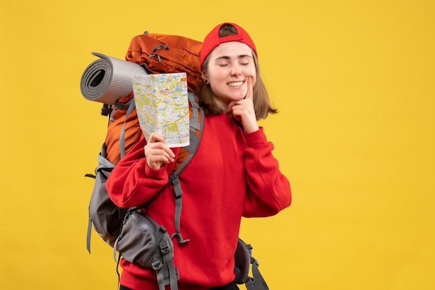 Vue de face souriant campeur femelle avec sac à dos rouge tenant la carte