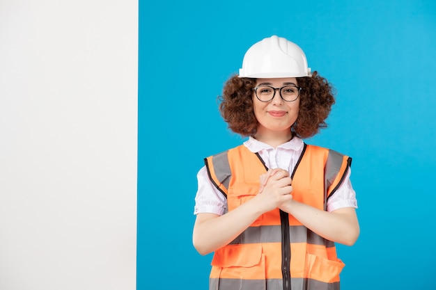 Vue de face souriant constructeur féminin en uniforme sur bleu