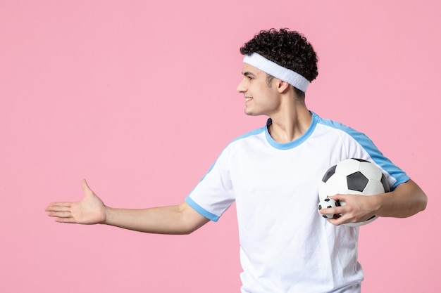 Vue de face souriant joueur de football dans des vêtements de sport avec ballon