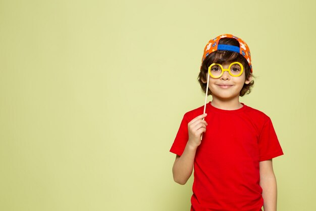 Une vue de face souriant mignon garçon adorable en t-shirt rouge sur l'espace de couleur pierre