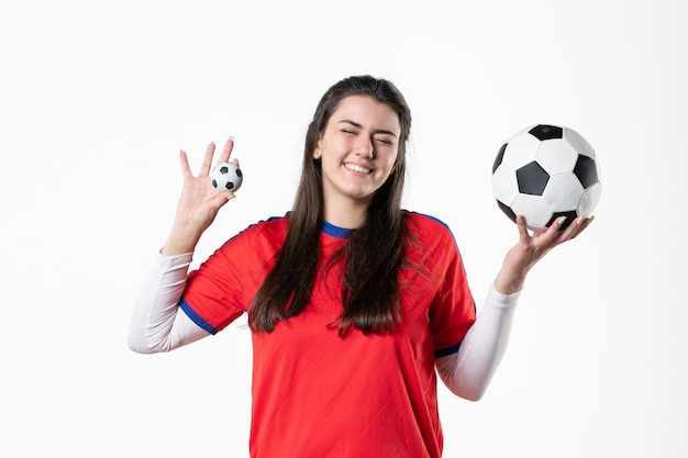 Vue de face souriante jeune femme en vêtements de sport avec ballon de foot