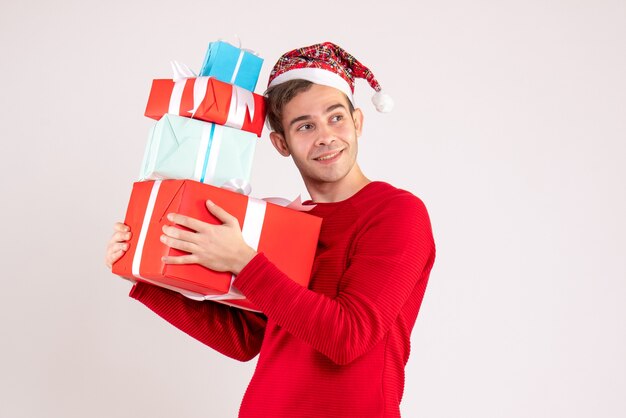 Vue de face sourit jeune homme avec bonnet de Noel debout sur blanc