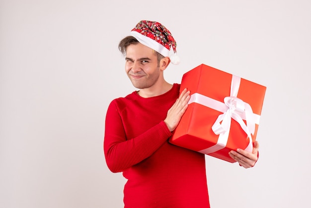 Vue de face sourit jeune homme avec bonnet de Noel debout sur blanc