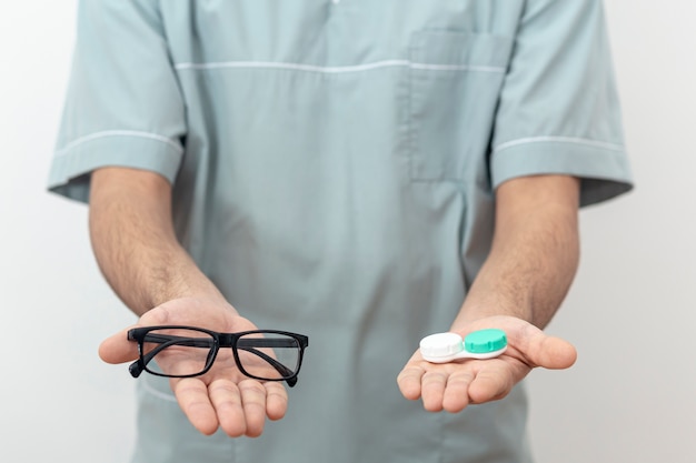 Vue de face d'un spécialiste des yeux tenant des lunettes et des lentilles de contact