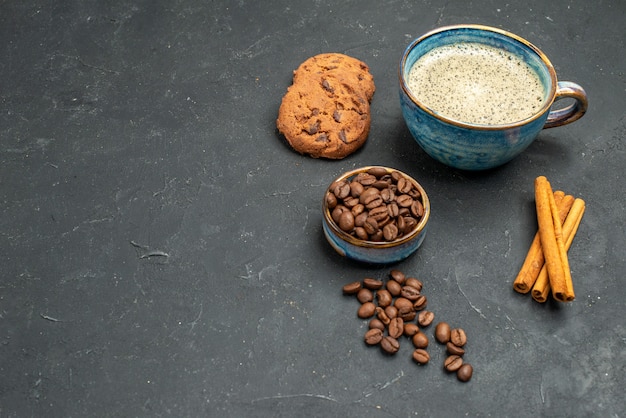 Vue de face une tasse de bol de café avec des graines de café bâtons de cannelle biscuits sur un endroit sombre et libre