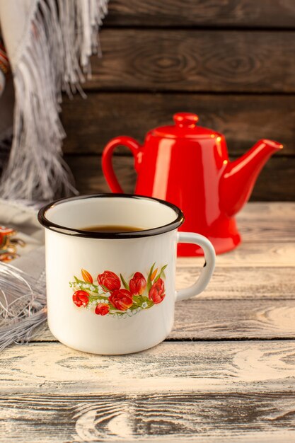 Vue de face d'une tasse de café avec une bouilloire rouge sur le bureau en bois